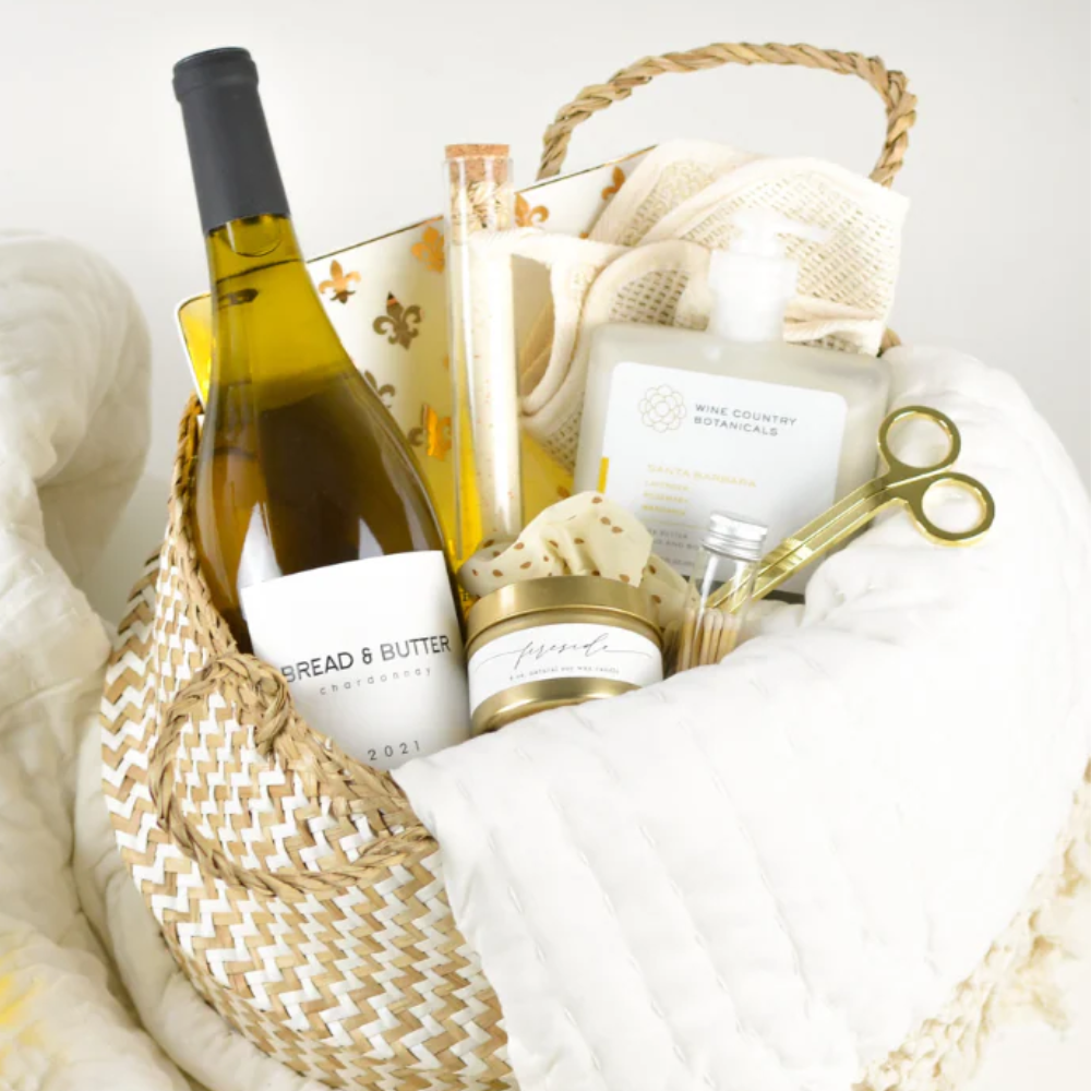 Gift basket with wine, candles, and other items on a white background